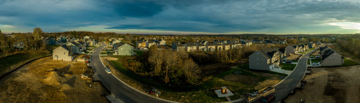 Aerial sunset panorama of luxury real estate development single family house neighborhood street with dramatic sky in Maryland USA