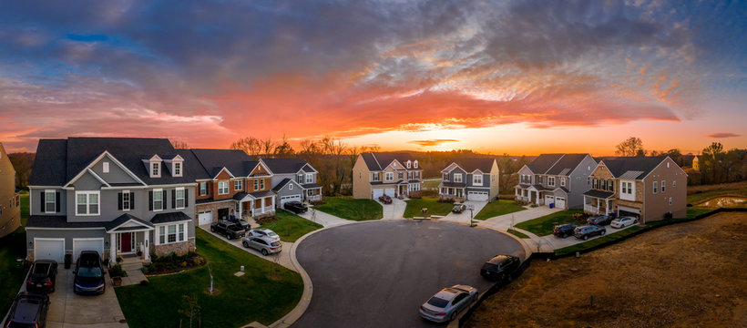 Aerial view of cul de sac neighborhood suburban street with luxury houses in upper middle class American real estate development in the USA stunning red, yellow, orange sunset color sky	