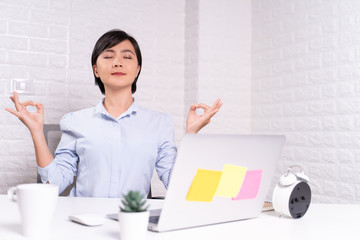 Woman meditating holding her hands in yoga gesture at office