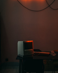 an old computer on a Desk with a neon sign