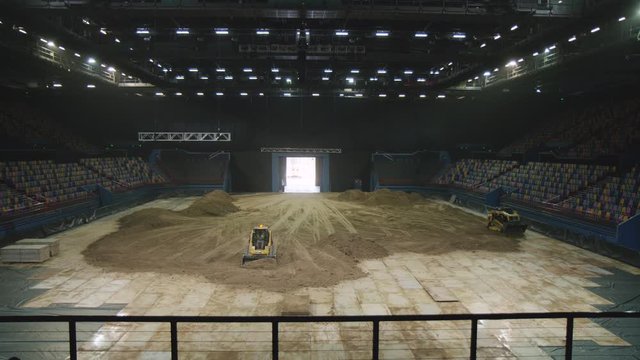 Shaping dirt inside indoor stadium in preparation for a supercross event