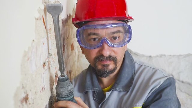 portrait of an adult man in a helmet on his head and with a perforator in his hand