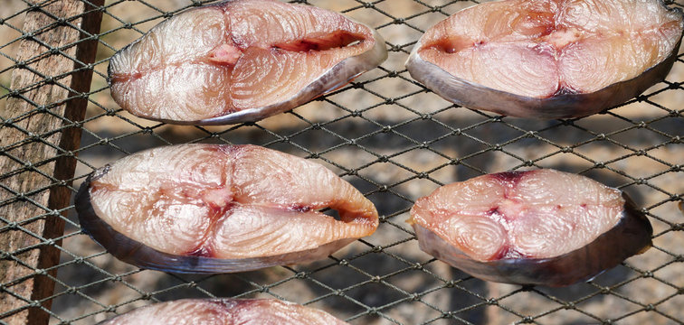 Pieces of King mackerel fish on the grill, Raw Sun-dried seafood in Thailand