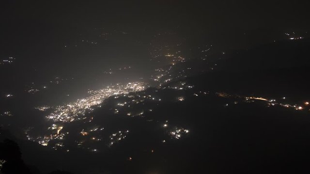 Night timelapse of a small city inside a valley with vehicles moving in and out of the city. Long exposure wide shot. Location: BesiSahar, Lamjung, Nepal.