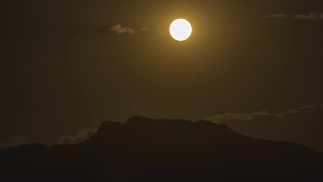 Night timelapse of a golden full moon rising over the top of a hill. Long exposure Tight shot. Location: Charikot Bazaar, Dolakha, Nepal.
