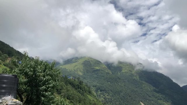Day timelapse of clouds movement over the top of a hill on a sunny day. Wide shot and was taken on the way to Poon Hill, Kaski, Nepal while trekking.