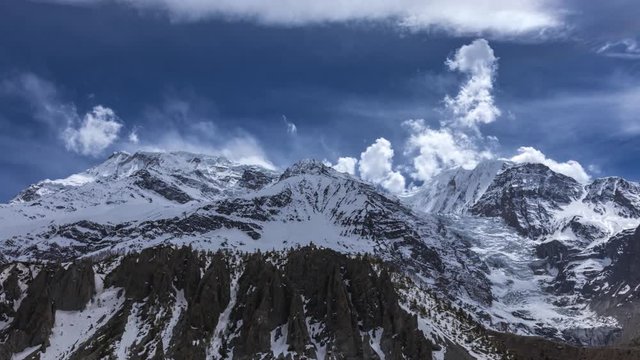 Day timelapse overlooking the Annapurna Mountain Range with clouds on a sunny day from Manang, Nepal. Wide shot.