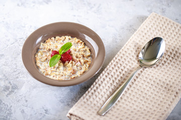 Baked granola with milk and raspberries with mint in a plate. Healthy breakfast. Tasty muesli, snack. top shot