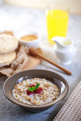 A healthy and dietary breakfast. Baked granola with milk and raspberries in a plate, whole grain breads and freshly squeezed juice. Delicious muesli.