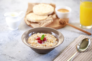 A healthy and dietary breakfast. Baked granola with milk and raspberries in a plate, whole grain breads and freshly squeezed juice. Delicious muesli.