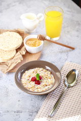 A healthy and dietary breakfast. Baked granola with milk and raspberries in a plate, whole grain breads and freshly squeezed juice. Delicious muesli.