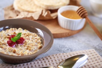 A healthy and dietary breakfast. Baked granola with milk and raspberries in a plate, whole grain breads and freshly squeezed juice. Delicious muesli.
