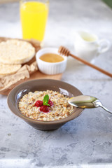 A healthy and dietary breakfast. Baked granola with milk and raspberries in a plate, whole grain breads and freshly squeezed juice. Delicious muesli.