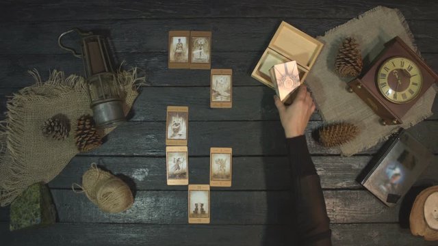 cartomancy and card reading. Top View.  Fortune-teller reads tarot cards. Сard fortunetelling layout lies on the table. Soothsayer puts beige deck of cards on table.