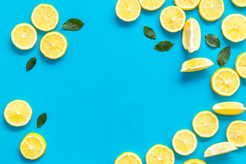 Lemon frame. Sliced citruses and leaves on blue background top view copy space