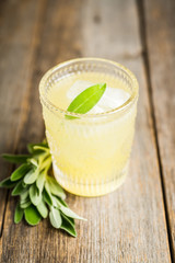 Gin based sweet old-fashioned cocktail mandarin juice and sage leaves on the rustic background. Selective focus. Shallow depth of field.