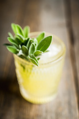 Gin based sweet old-fashioned cocktail mandarin juice and sage leaves on the rustic background. Selective focus. Shallow depth of field.