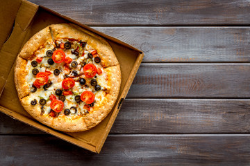 Order pizza to home or office. Italian food in box on dark wooden background top view copy space