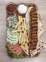 Kebab. Traditional middle eastern, arabic or mediterranean meat kebab with vegetables, fresh onion and herbs and french fries. Overhead view