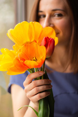 beautiful brunette girl with yellow tulips in her hands
