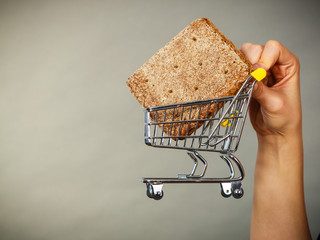 Woman hand holding shopping cart with bread