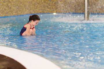 happy little girl in the pool of the water park. Child learns to swim. teaching a child to swim