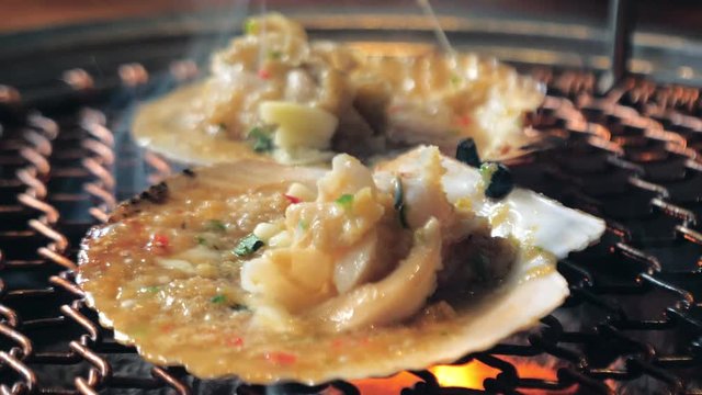 Big fresh scallop shell seafood grill on metal net with charcoal, barbecue in korean restaurant. Barbecue cooking style