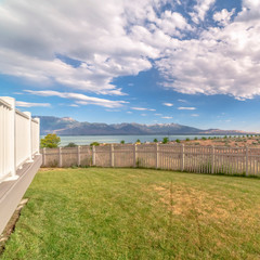 Square Bakyard with white wooden fence overlooking a scenic view of lake and mountain