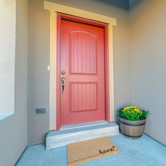 Square frame Red wooden front door at the entrance of a home with concrete exterior wall