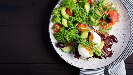 Healthy breakfast. Sandwiches with cream cheese, avocado, boiled egg and smoked salmon on plate. Top view, overhead