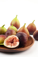 fig fruits and one cut figs in wooden bowl on white background