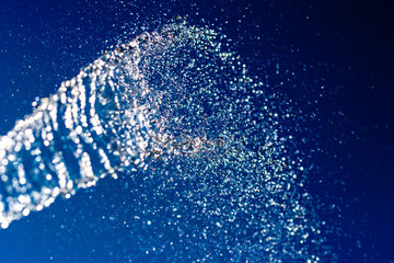 Abstract background. A stream of water with splashes sparkles on a blue background. Motion blur....