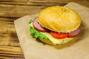 Fresh delicious homemade cheeseburger on brown paper on wooden table