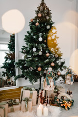 Decorated Christmas interior. Christmas tree with gifts boxes in a white room. Fir-tree decorated with garlands. Decor. Happy New Year and Merry Christmas. The concept of winter holiday.