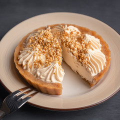 Cut cake basket with caramel on a plate with a fork for dessert on a black wooden background.