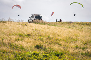 Beautiful mountain landscape with clouds. The top of Gimba Mountain in the Carpathians. People relax and paraglide in the cloudy sky above the mountains.