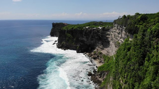 Aerial: flying trough the ocean, waves breaking on the cliff, Uluwatu, Bali