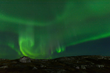 Aurora borealis over the hills. At night in the sky in the north.
