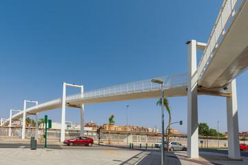 Fototapeta na wymiar Light white footbridge over the railway tracks to the station.