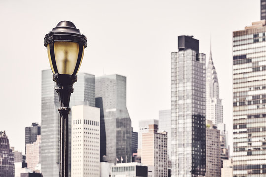 Retro Toned Picture Of A Street Lamp With New York City Blurred Skyline In Background, USA.