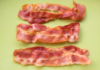 Cooked bacon rashers on green plate