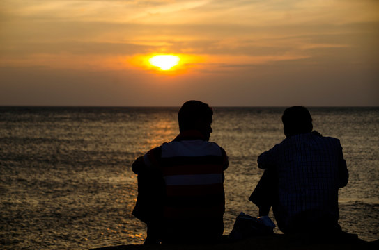 silhouette of man sitting on the beach at sunset