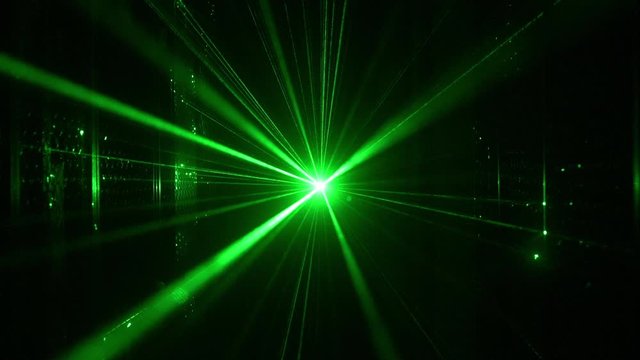 Nightclub laser with green rays in motion shooting through haze