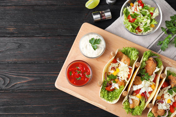 Delicious fish tacos served on dark wooden table, flat lay