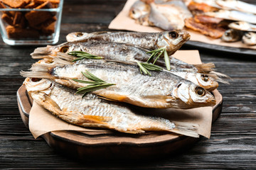 Tasty dried fish with rosemary on black wooden table