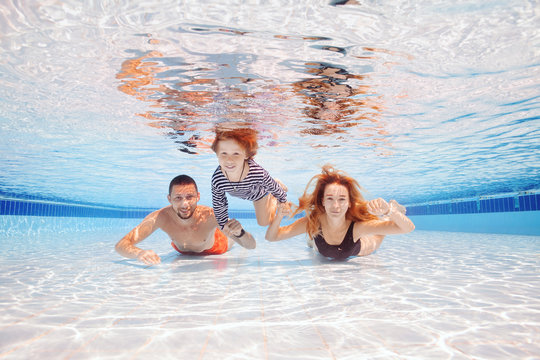 Happy young boy swim and dive underwater with parents, kid breaststroke with fun in pool. Active healthy lifestyle, water sport activity and lessons summer family vacation with child.