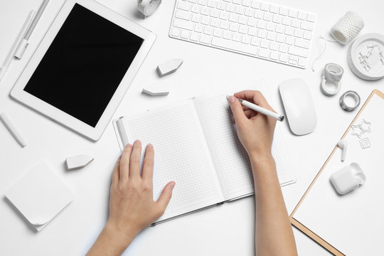 Professional designer working at white table, top view.