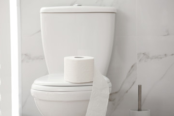 Obraz na płótnie Canvas Modern toilet bowl with roll of paper in bathroom