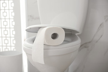 Paper roll on toilet bowl in bathroom