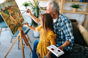 Senior man, grandfather and his grandchild drawing, painting together. Happy family time
